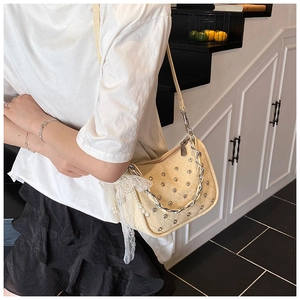 Détail du sac beige matelassé avec rivets argentés et accessoire nœud en perles et dentelle