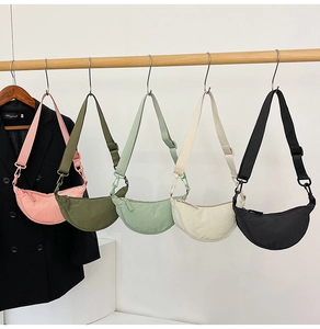 Detailed row of nylon crescent crossbody bags in pink green cream and black with straps