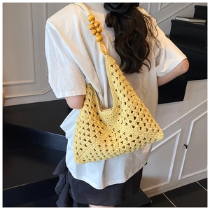 Shoulder bag detail featuring bright yellow crochet weave and wooden bead accents