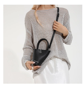 Détail du sac seau en cuir grainé noir avec coupe asymétrique et lettrage mode élégant