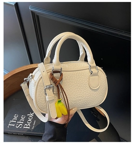 Detail of cream boston bag with crocodile texture, dual handles and banana charm