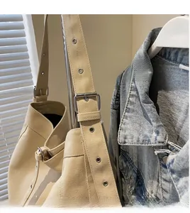 Detail of adjustable canvas strap with silver eyelets and metal buckle on beige tote