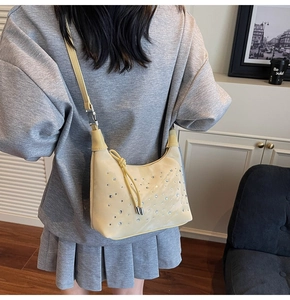 Close-up of beige pleated shoulder bag with silver rhinestones and drawstring detail
