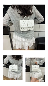 Détail d'un sac à main matelassé blanc avec étoile argentée et rivets métalliques