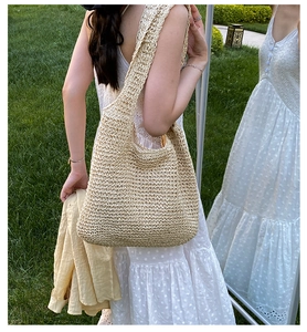 Close-up of beach woven tote bag with hollow texture shown on shoulder in garden