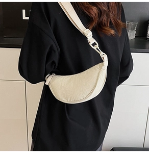 Detail of cream white crescent moon bag with wide strap and textured nylon fabric