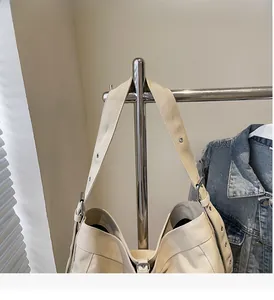 Detail view of beige canvas tote bag showing wide shoulder strap and metal buckle