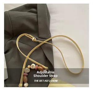 Dettaglio tracolla regolabile e perline effetto marmo su borsa a secchiello beige