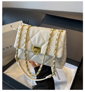 Detailed view of white quilted crossbody bag with gold chain and twist lock in gift box