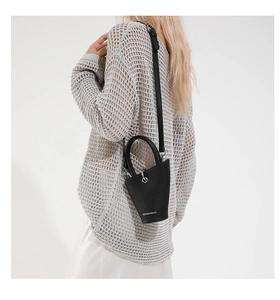Détail d'un sac seau noir en cuir foulonné avec slogan blanc et style mannequin