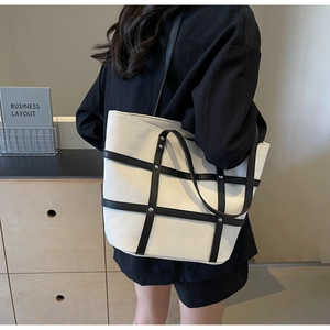 Detail view of large contrast tote bag with silver studs worn on shoulder
