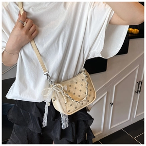 Détail du sac bandoulière crème avec chaîne argentée, strass et breloque en dentelle