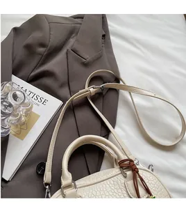 Detail showing creamy white textured leather handbag with a brown tassel zipper pull