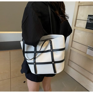 Detailed view of canvas tote bag with contrast leather trim and metal stud accents