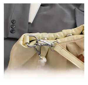 Dettaglio del gancio in metallo e perla marmorizzata sulla borsa beige a pieghe