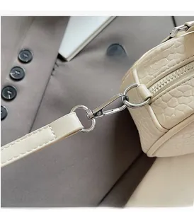 Detail of creamy crocodile pattern leather with polished silver metal buckle and zipper