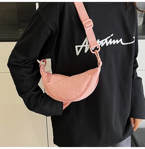 Close-up of pink nylon crossbody bag with adjustable wide strap on black sweatshirt
