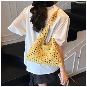 Détail du sac à épaule en tricot évidé jaune avec de grandes perles en bois sur la bandoulière