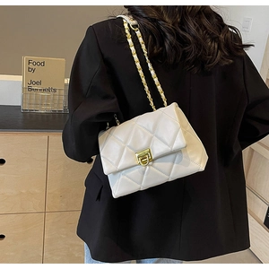 Detail of quilted diamond pattern on beige shoulder bag with golden chain and clasp