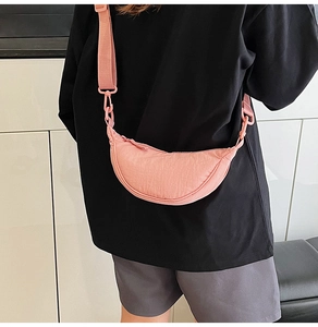 Pink nylon half-moon crossbody bag with wide adjustable strap and pleated texture detail