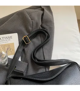 Detail of adjustable shoulder strap with gold buckle on black leather hobo bag