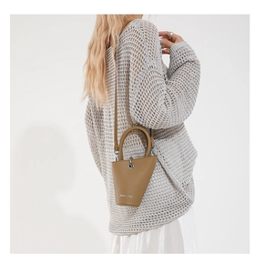 Détail d'un sac seau en cuir kaki avec anneaux métalliques argentés et bandoulière réglable