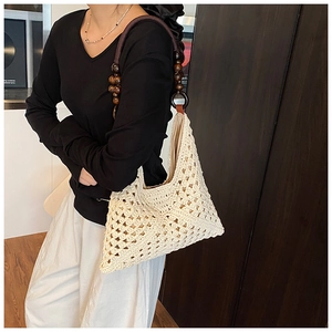 Detail of hollow crochet texture on woven tote bag with brown wooden bead shoulder strap