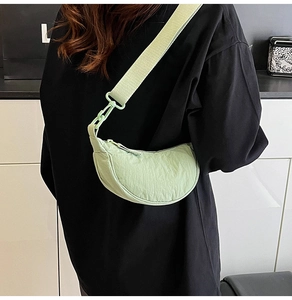 Detailed close-up of light green nylon crescent bag with adjustable wide fabric strap