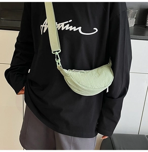 Close-up of light green nylon crescent crossbody bag showing textured fabric and wide strap