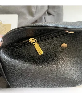 Close-up of polished gold zipper puller on premium black pebbled leather tote bag
