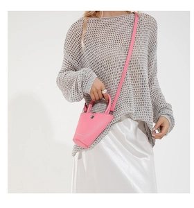Petit sac seau rose en cuir grainé avec bandoulière fine et poignée sur mannequin
