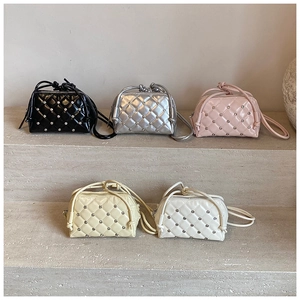 Detail of five mini quilted leather crossbody bags with rhinestone studs on stone steps