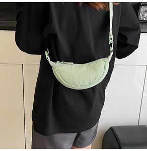 Close-up of light green nylon dumpling bag with adjustable strap and wrinkled texture