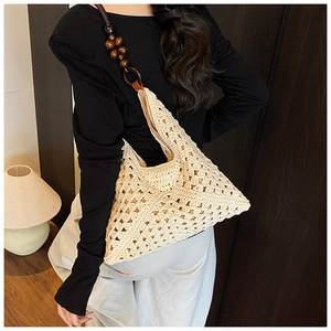 Detalle de bolso beige tejido a mano con asa de cuentas de madera y patrón de ganchillo