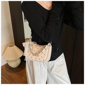 Sac à bandoulière crème chic avec clous et perle porté par un mannequin pour le style