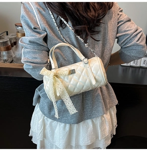 Gros plan du sac cylindrique blanc matelassé avec nœud en dentelle et chaîne