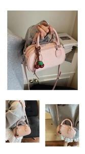 Close-up of pink Boston bag with cherry charm and textured leather detail