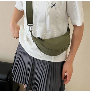 Close-up of green nylon crescent bag with adjustable wide strap and matte buckle detail