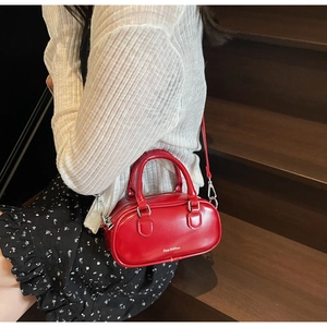 Close-up of a small red Boston bag with twin handles and silver hardware for women