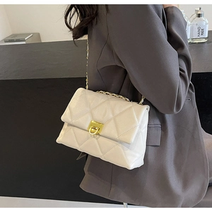 Détail du sac à bandoulière matelassé crème avec chaîne dorée et fermoir pivotant
