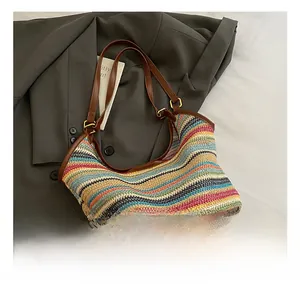 Close-up of colorful striped straw tote with premium brown leather handles and gold metal buckles