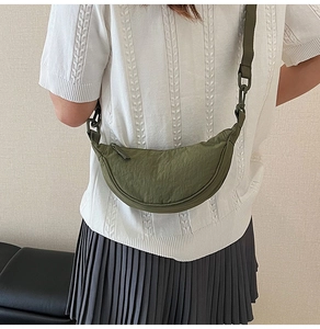 Army green nylon crescent crossbody bag shown in a top-down lifestyle perspective