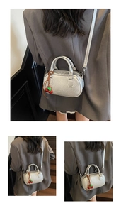 Close-up of silver mini pillow bag with crocodile pattern and red cherry charm