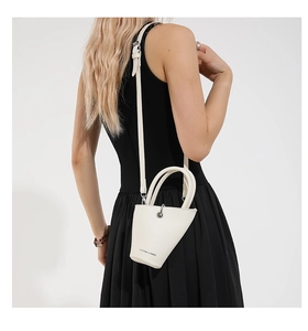 Détail du mini sac seau blanc en cuir grainé avec anneaux argentés et texte décoratif