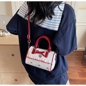 Model wearing a red and white Boston bag with bow details and heart pendant