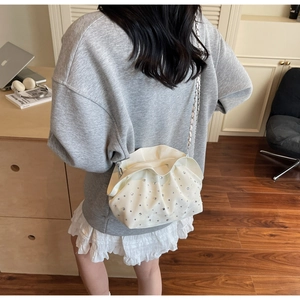 White ruched dumpling bag with rhinestones and metal chain strap worn by a model