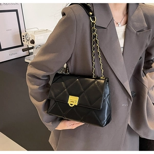 Detail of classic quilted shoulder bag with gold clasp worn by a model in a retro setting