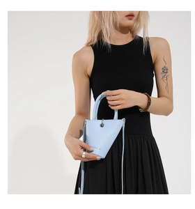 Détail du sac seau en cuir bleu clair montrant le fini texturé et le décor en anneau