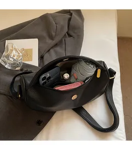 Detail showing spacious interior of black pebble leather bag with daily essentials