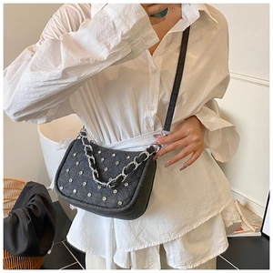 Détail du sac à bandoulière punk clouté avec strass porté sur une chemise